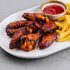 Delicious fried chicken wings with golden french fries and ketchup on a white plate